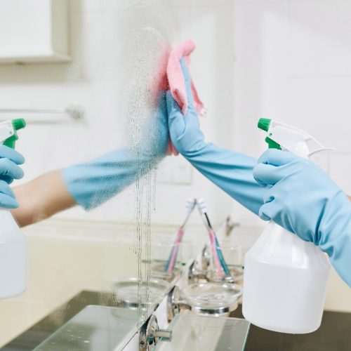 Woman cleaning bathroom mirror